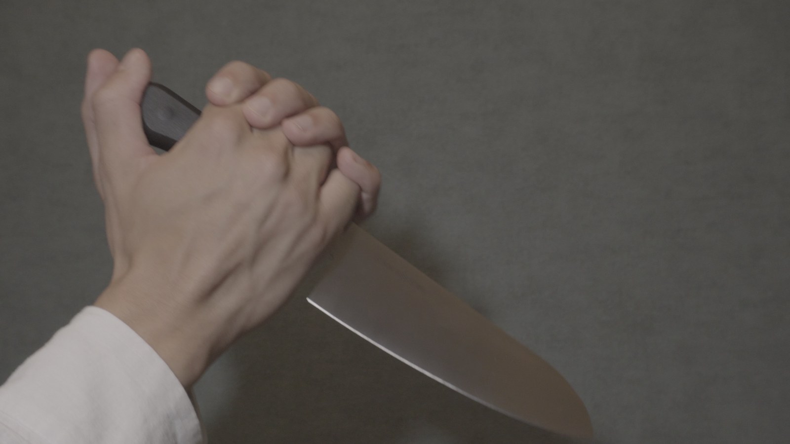 Ungraded S-Log2 footage of a hand holding a kitchen knife against a wall: flat, grey, low contrast