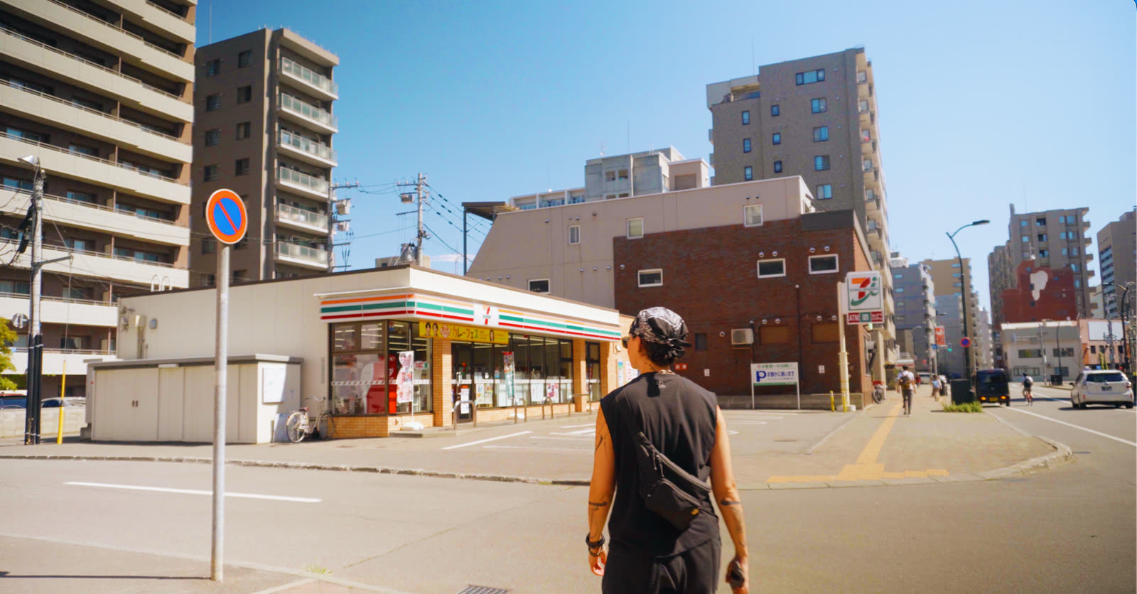The same street corner through the Sora LUT: airy turquoise sky, warm brick and skin tones